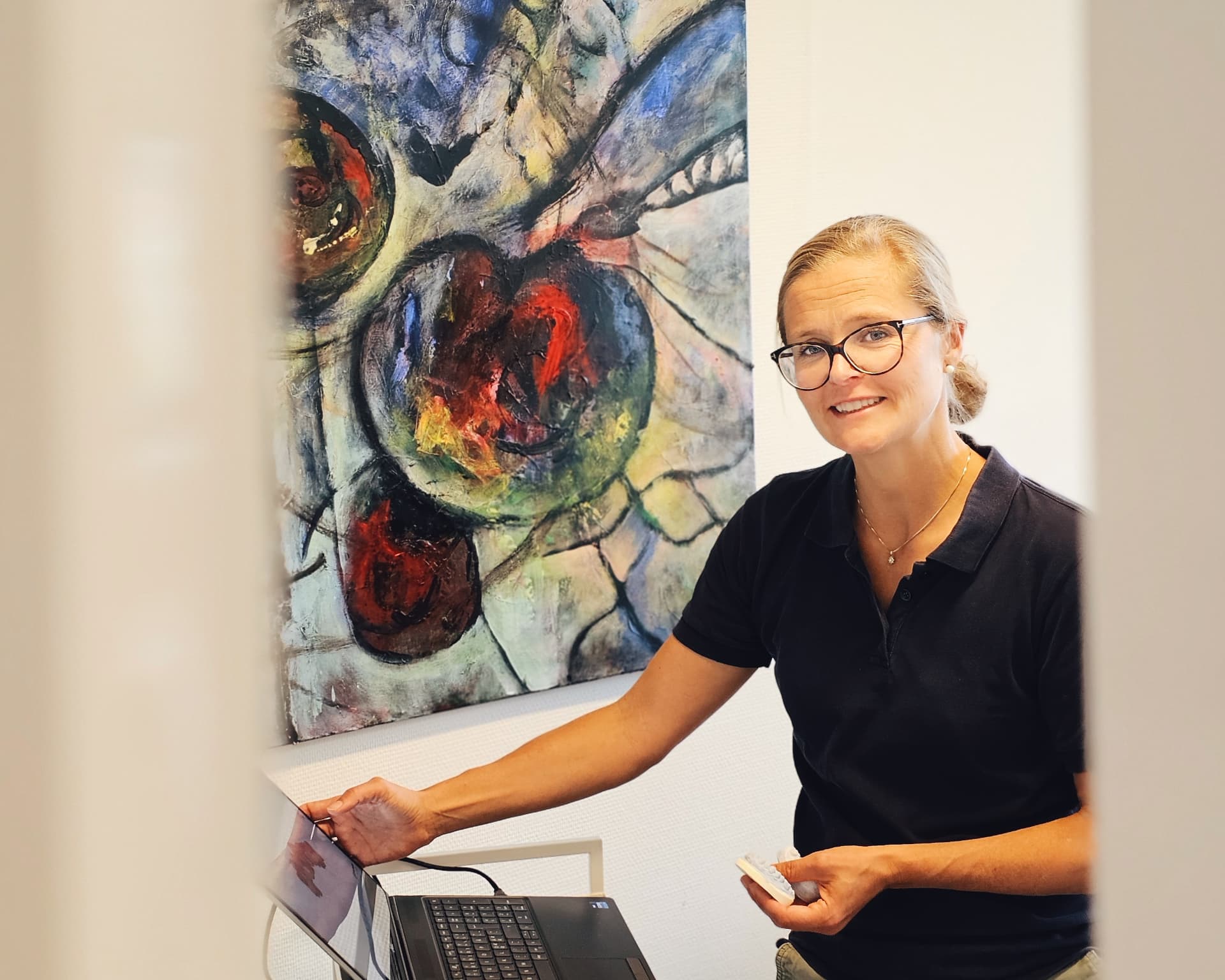 Medarbejder i klinikken ved et kunstværk og en computer