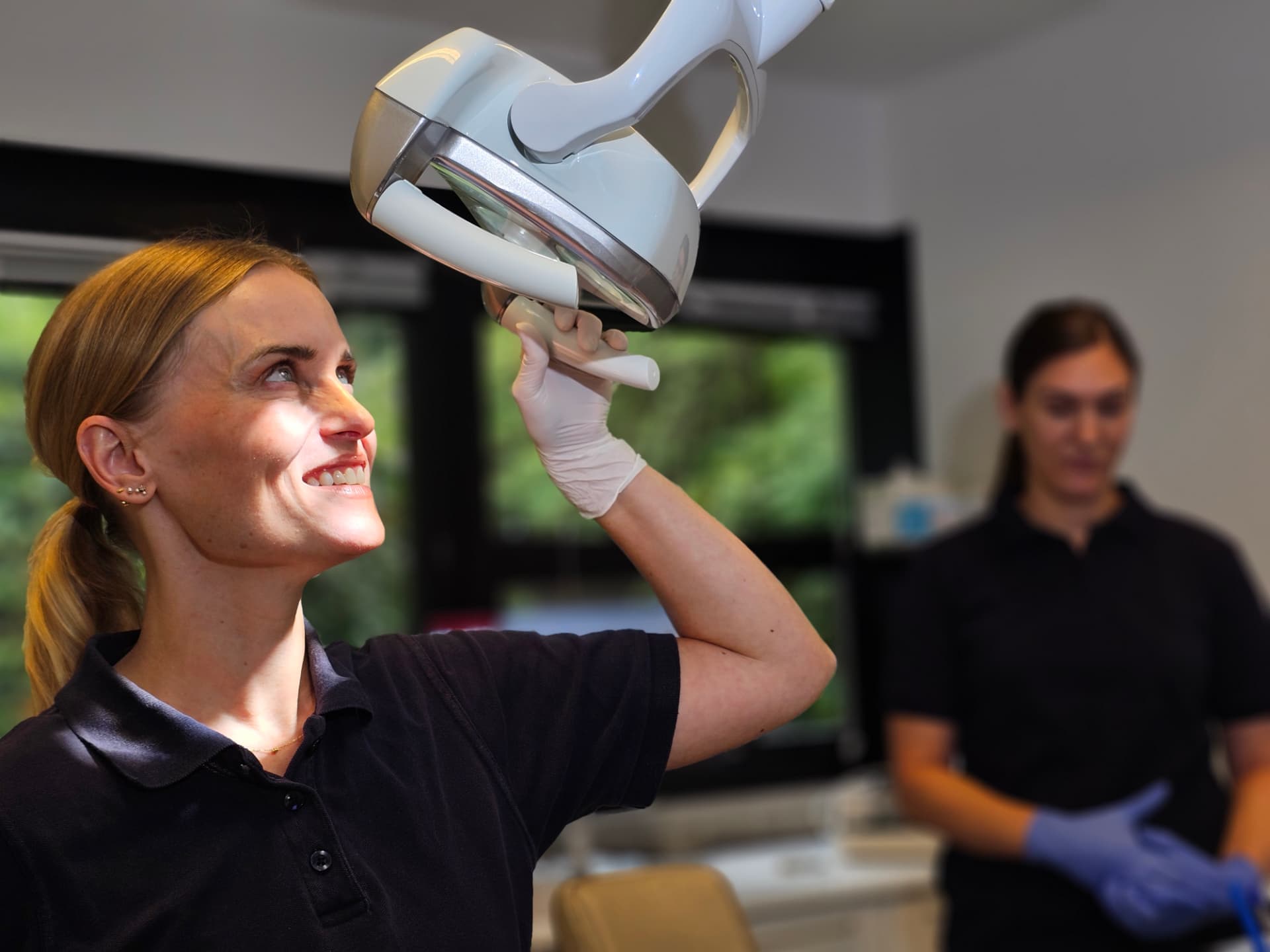 Tandlæge Anne Palgaard smiler, mens hun indstiller operationslampen på Holte Tandklinik